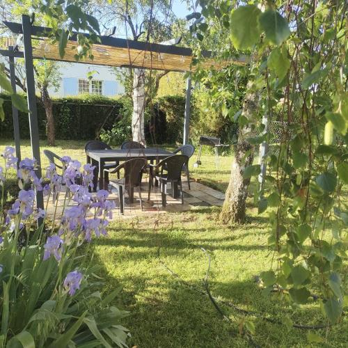 a picnic table in a garden with purple flowers at charmante maison entre mer et campagne in La Jarrie