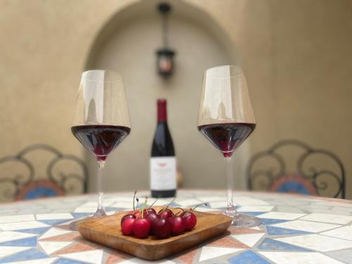 dwa kieliszki wina i wiśnie na stole w obiekcie Highland Forest Zimmers w mieście El-Rom