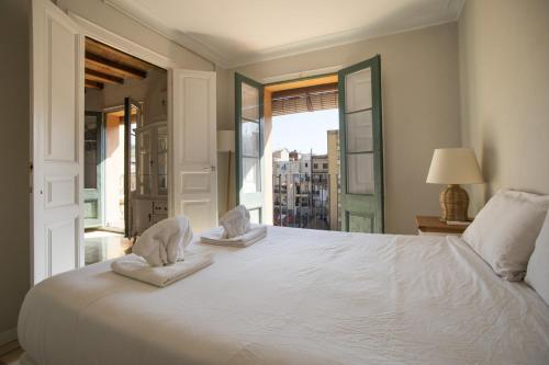 a bedroom with a large white bed with a window at 41COB1019- Charming rustic apartment in Barcelona