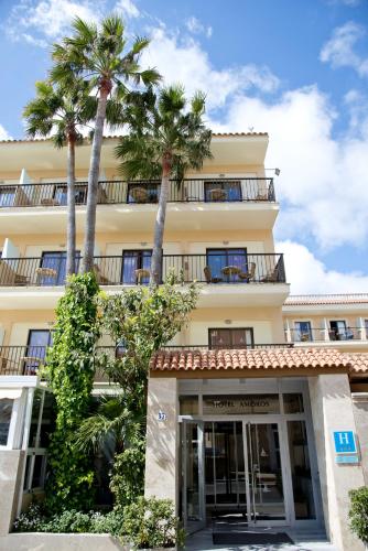 a building with palm trees in front of it at Hotel Amoros in Cala Ratjada