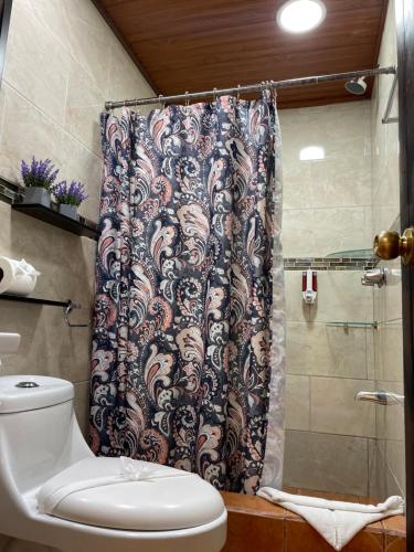 y baño con cortina de ducha y aseo. en Cabinas Vista Al Golffo, en Monteverde