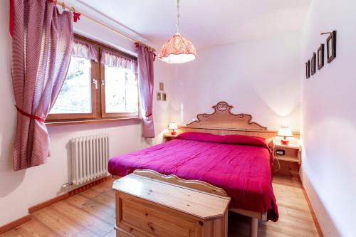 ein Schlafzimmer mit einem großen Bett mit einer roten Tagesdecke in der Unterkunft Sass Pordoi in Mazzin