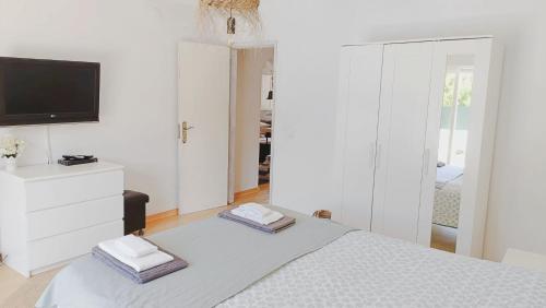 a white bedroom with a bed and a tv at Casa da Lagoa in Sesimbra