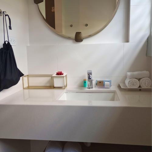 a white bathroom with a sink and a mirror at Trópica Beach Hotel in San Juan
