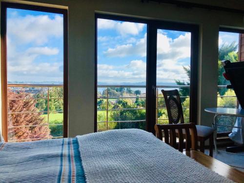 1 dormitorio con cama y ventanas grandes con vistas. en Suite abierta todo el año con vistas al campo, lago y ciudad, en Puerto Varas