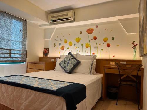 a bedroom with a bed with a desk and a wall with flowers at Tainan Canal Guest House in Anping