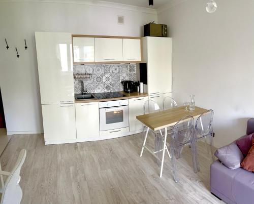 cocina con armarios blancos, mesa y sofá en Apartment Chambre Nowolipki, en Varsovia