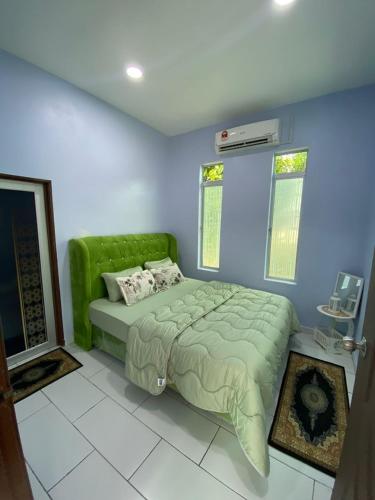 Schlafzimmer mit grünem Bett und blauen Wänden in der Unterkunft HOMESTAY JERAI GEOPARK in Guar Chempedak