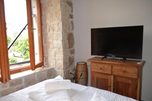 een slaapkamer met een flatscreen-tv op een houten dressoir bij VILLA MOST Tisno in Tisno