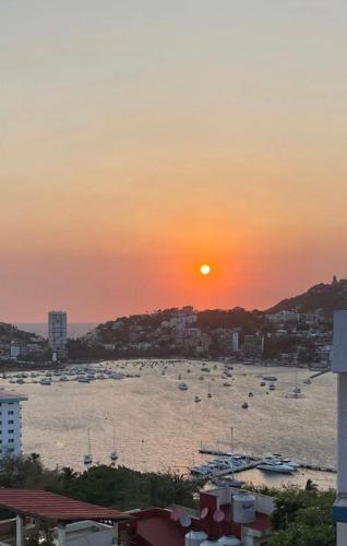 a sunset over a beach with boats in the water at Casa con vista espectacular al mar con alberca in Acapulco