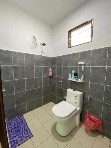 a bathroom with a white toilet and a window at HOMESTAY JERAI GEOPARK in Guar Chempedak