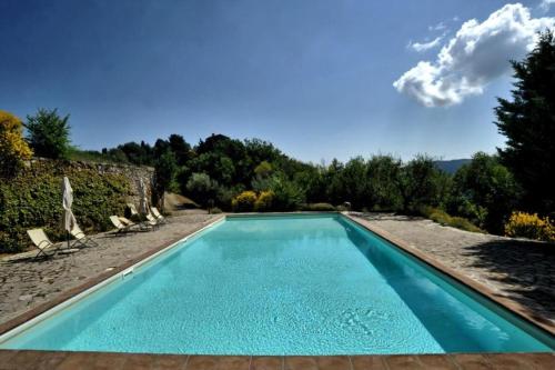 una piscina azul con sillas y árboles en Castello di Gaiche, en Collebaldo