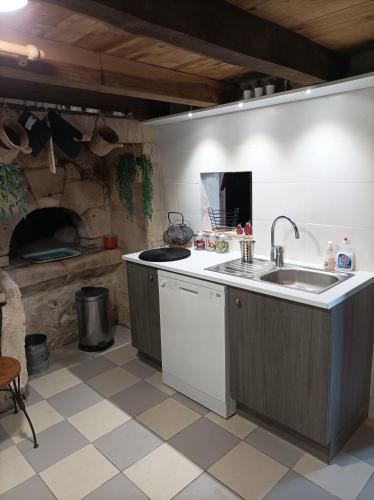 une cuisine avec un évier et une cuisinière four supérieur dans l'établissement Gite des Perreyeurs - maison troglodyte avec vue sur Loire, à Montsoreau