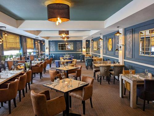 um restaurante com mesas e cadeiras num quarto em The Wildings Hotel & Tudno's Restaurant em Llandudno