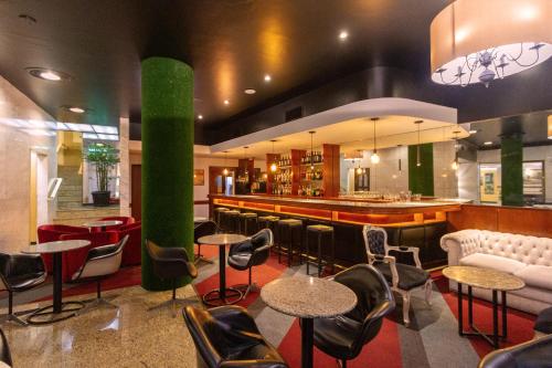 a lobby with a bar with chairs and tables at Curitiba Palace Hotel in Curitiba
