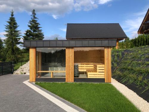 a small house with a black roof on top of grass at Świerkowa Osada in Istebna