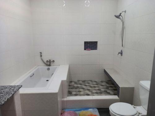 La salle de bains blanche est pourvue d'une baignoire et de toilettes. dans l'établissement kdk villa, à Buccoo