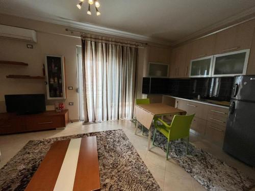 uma cozinha com uma mesa e cadeiras verdes num quarto em Harbor Apartment em Vlorë