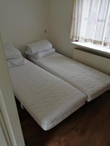 two twin beds in a room with a window at Recreatiepark Maas en Bos in Wellerlooi
