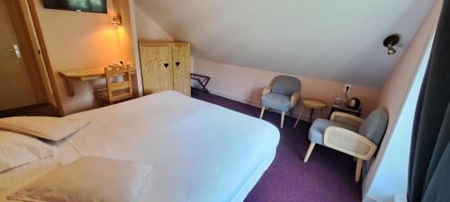a bedroom with a white bed and two chairs at Alti'Pic Hôtel in Le Mont-Dore
