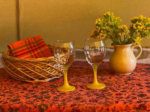 two wine glasses and a vase with flowers on a table at Pädaste Aerga Sunset Glamping in Pädaste