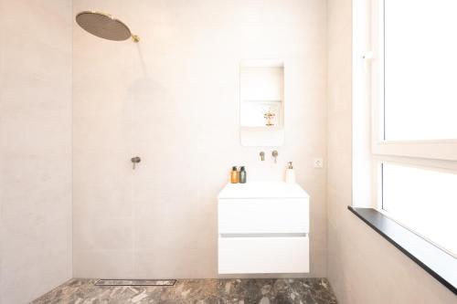 La salle de bains blanche est pourvue d'un lavabo et d'un miroir. dans l'établissement Newly build Utopia The Den Apartment 7-Minutes From Rotterdam City app2, à Schiedam