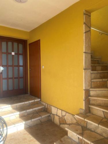 a yellow wall with stairs next to a door at Villa Una Apartments in Labin