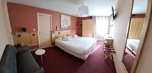 1 dormitorio con cama blanca y sofá en Alti'Pic Hôtel, en Le Mont-Dore