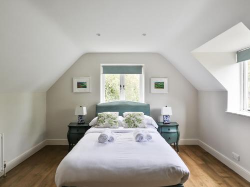 a white bedroom with a bed and two night stands at Friesland Cottage in Shilton