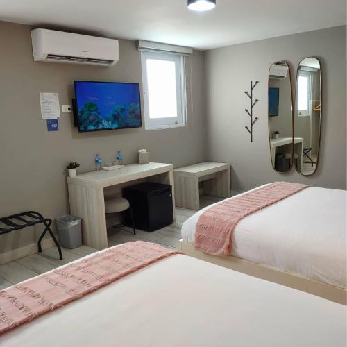 a bedroom with two beds and a desk and a tv at Trópica Beach Hotel in San Juan