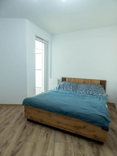 a bed in a white room with a wooden floor at Apartament Flat 33 Suwałki in Suwałki