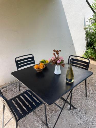 a black table with a bowl of fruit and a vase of flowers at Home Cassis - Maison Les Calanques - Piscine chauffée à 30c in Cassis