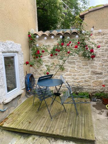 een tafel en een stoel op een houten terras met rozen bij Maison confortable in Espéraza