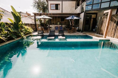 a swimming pool with two chairs and an umbrella at Pousada Zama in Camburi
