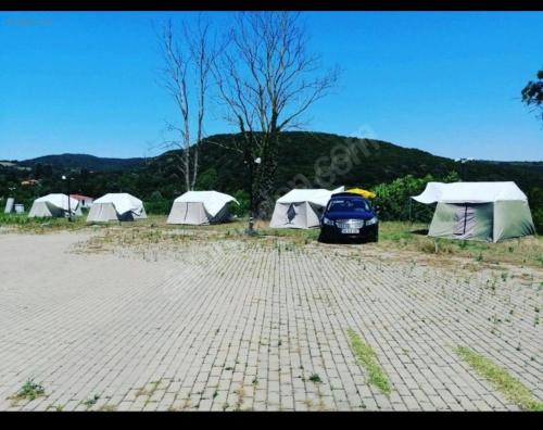 a group of tents and a car parked in a parking lot at Yılmaz camping 