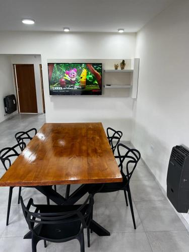 einen Holztisch mit Stühlen und einen TV an der Wand in der Unterkunft URIBURU 45 in Malargüe