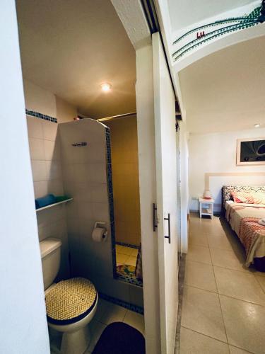 a bathroom with a toilet and a bed in a room at CASA MOSAICO in Puerto López