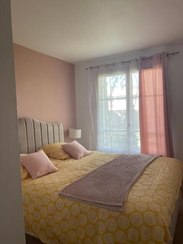 a bedroom with a bed with pink pillows and a window at Résidence du Parc Near Disneyland Paris in Serris