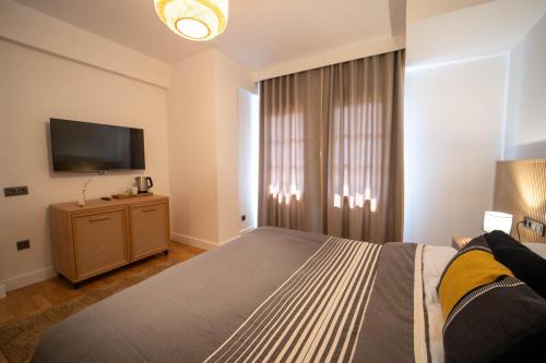 a bedroom with a bed and a flat screen tv at Hotel Club-E in Fethiye