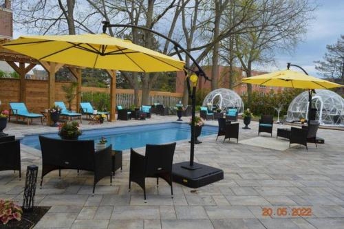 a pool with tables and chairs and yellow umbrellas at Lakehurst Estate in Cobourg