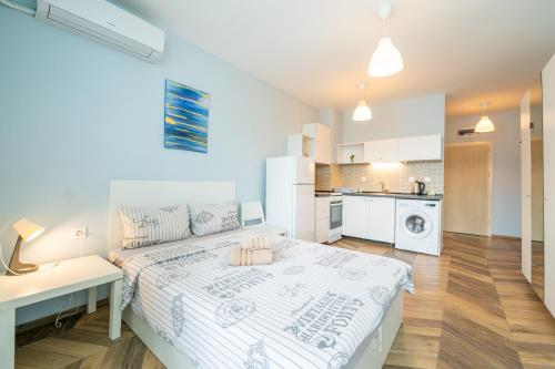 a white bedroom with a bed and a kitchen at Cozy little apartment in Studentski grad in Sofia