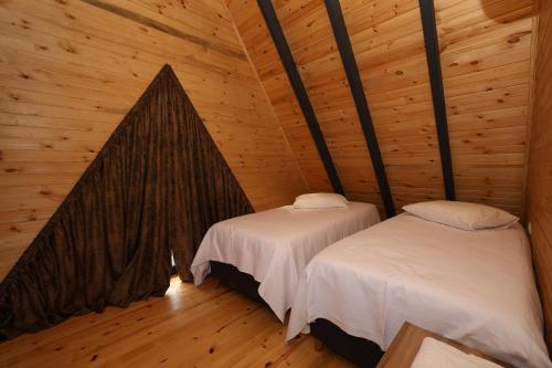 um quarto com 2 camas num chalé de madeira em Azhara Bungalov em Pelitli