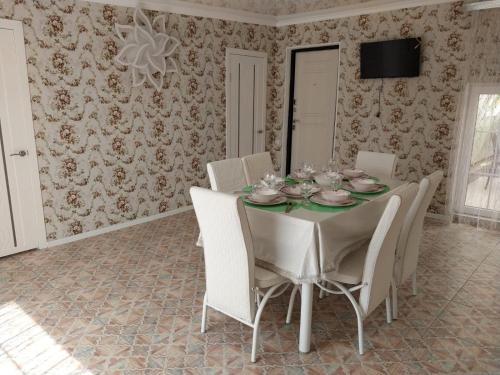 a dining room with a table and white chairs at Апарт-Отель Энглер in Novorossiyskoye