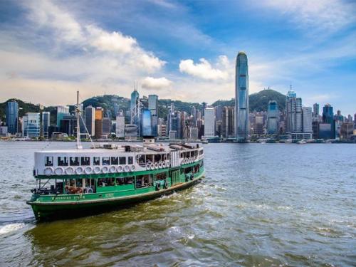 a green and white boat on the water in front of a city at 香港太阳宾馆 in Hong Kong