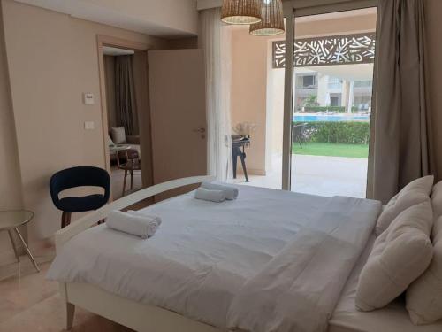 Cette chambre comprend un grand lit blanc et une fenêtre. dans l'établissement Mangroovy - Delicate 1BR Ground floor by the Pool, à Hurghada