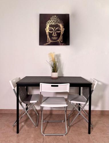 une table noire avec des chaises blanches et une peinture de tête dans l'établissement C016 Appartement 10 MIN de Disneyland Paris, à Montévrain