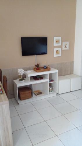 ein Wohnzimmer mit einem weißen Entertainment-Center mit einem Flachbild-TV in der Unterkunft Penedo Flats in Penedo