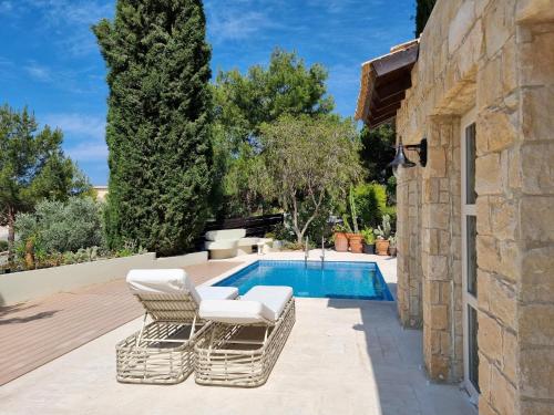 un patio con 2 sillas y una piscina en EXQUISITE GOLF VILLA with Sea, 8Tee, Green Views, in Aphrodite Hills Golf Resort en Kouklia