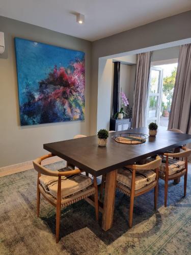 a dining room table and chairs with a painting on the wall at EXQUISITE GOLF VILLA with Sea, 8Tee, Green Views, in Aphrodite Hills Golf Resort in Kouklia