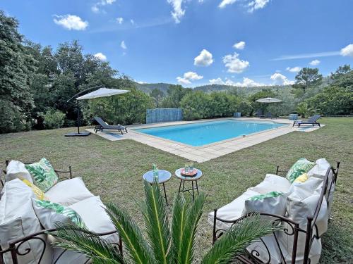 une cour arrière avec une piscine avec des chaises et une table dans l'établissement Mas Benoit, à Salernes